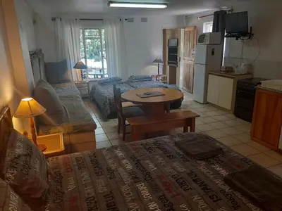 a living room with a bed and a kitchen at Luilekker Chalets in Waterval-Onder
