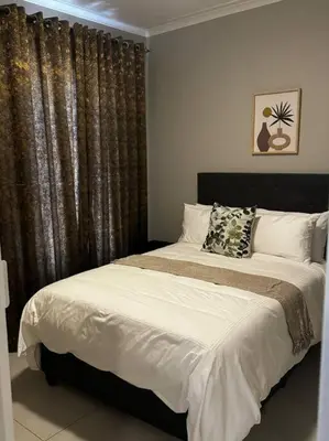 a bedroom with a bed and a window with curtains at The Pebbles in Midrand