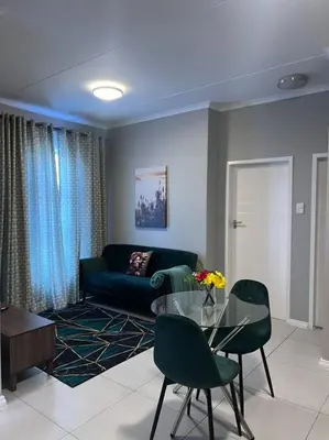 a living room with a glass table and green chairs at The Pebbles in Midrand