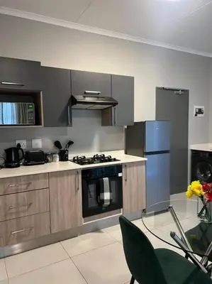 a kitchen with stainless steel appliances and a glass table at The Pebbles in Midrand