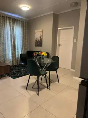 a living room with a glass table and chairs at The Pebbles in Midrand