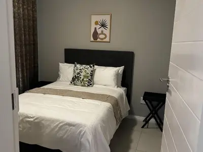 a bed with a black headboard in a bedroom at The Pebbles in Midrand