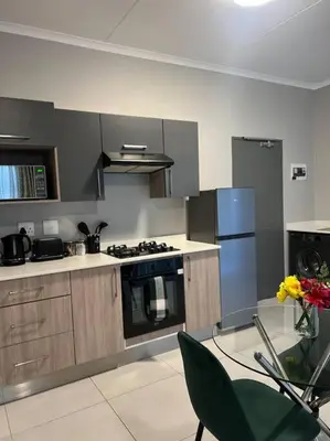 a kitchen with a stove and a refrigerator at The Pebbles in Midrand