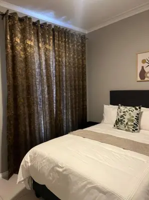 a bedroom with two beds and a window with curtains at The Pebbles in Midrand