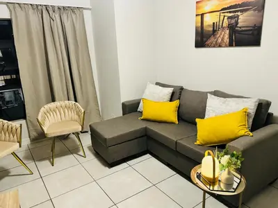 a living room with a gray couch and yellow pillows at The Blyde Luxury Apartment in Pretoria