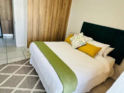 a bed with yellow and green pillows on it at The Blyde Luxury Apartment in Pretoria