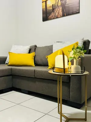 a grey couch with yellow pillows and a table at The Blyde Luxury Apartment in Pretoria