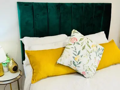 a bed with yellow pillows and a green headboard at The Blyde Luxury Apartment in Pretoria