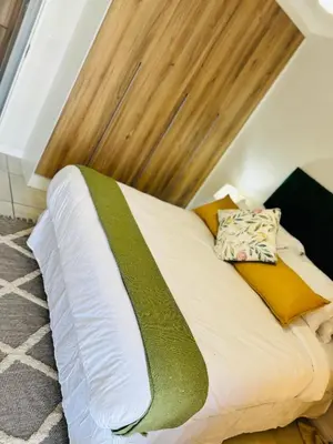 a bed with a green and white sheets and pillows at The Blyde Luxury Apartment in Pretoria