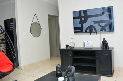 a living room with a black dresser and a mirror at Home for Us Self catering in Duvhapark