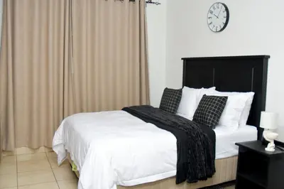 a bedroom with a bed with a clock on the wall at Home for Us Self catering in Duvhapark