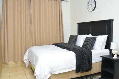 a bedroom with a bed and a clock on the wall at Home for Us Self catering in Duvhapark