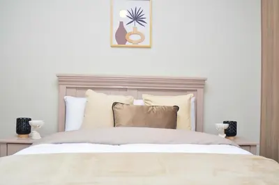 a white bedroom with a large bed with pillows at Home for Us Self catering in Duvhapark