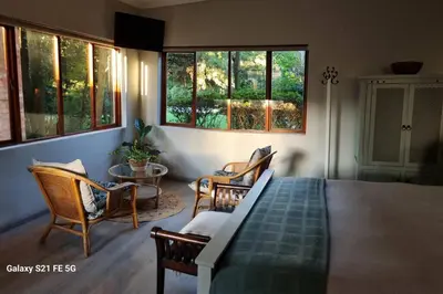 a bedroom with a bed and chairs and windows at Nel's Studio in Benoni