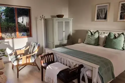 a bedroom with a bed and two chairs and a window at Nel's Studio in Benoni