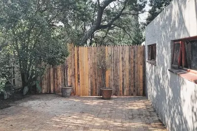 a wooden fence with two trash cans in front of it at Nel's Studio in Benoni