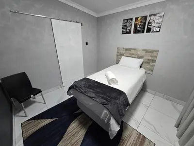 a small bedroom with a bed and a chair at Impala Palms Guesthouse in Modimolle