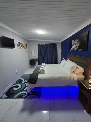 a bedroom with a large bed with blue lighting at Impala Palms Guesthouse in Modimolle