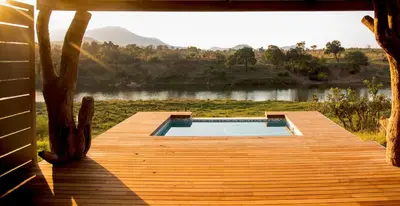 a wooden deck with a swimming pool on a lake at Simbini Sunset Cottage in Malelane