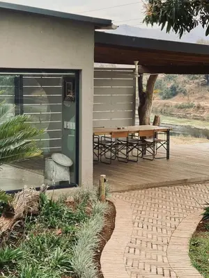 a house with a wooden deck with a picnic table at Simbini Sunset Cottage in Malelane