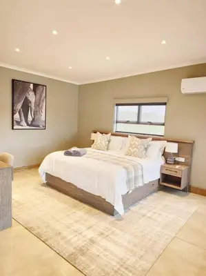 a bedroom with a large bed and a window at Simbini Sunset Cottage in Malelane