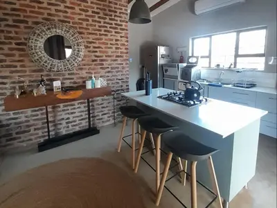 a kitchen with a counter and stools in a room at The Hedgehog at Marloth Park in Marloth Park