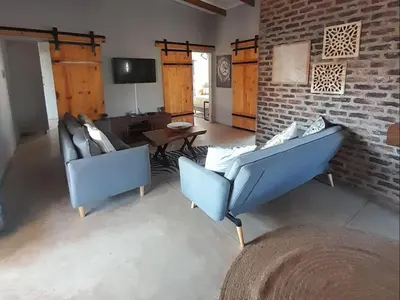 a living room with two blue chairs and a brick wall at The Hedgehog at Marloth Park in Marloth Park