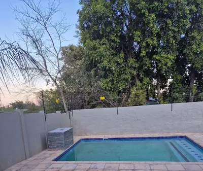 a swimming pool in a backyard with a fence at AndriMat Villa Harties in Hartbeespoort