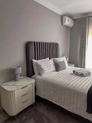 a bedroom with a bed with a large headboard and a night stand at AndriMat Villa Harties in Hartbeespoort