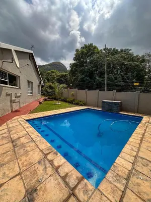 a blue swimming pool in front of a house at AndriMat Villa Harties in Hartbeespoort