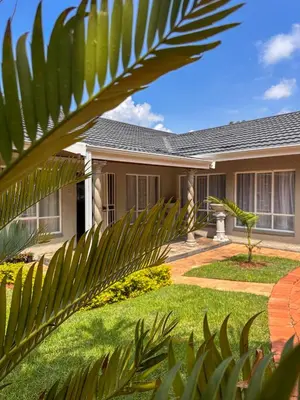 a house with a palm tree in front of it at AndriMat Villa Harties in Hartbeespoort