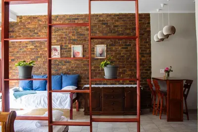a bedroom with a loft bed and a brick wall at Earthy Inn in Pretoria
