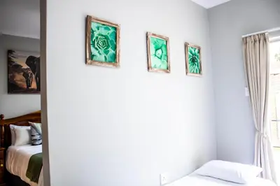 a bedroom with three framed paintings on the wall at Earthy Inn in Pretoria