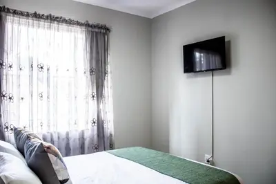 a bedroom with a bed and a television on a wall at Earthy Inn in Pretoria