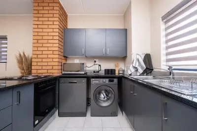 a kitchen with a washing machine and a sink at The Ridge View in Midrand