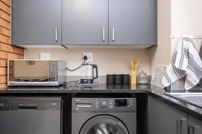 a kitchen with white cabinets and a washer and dryer at The Ridge View in Midrand