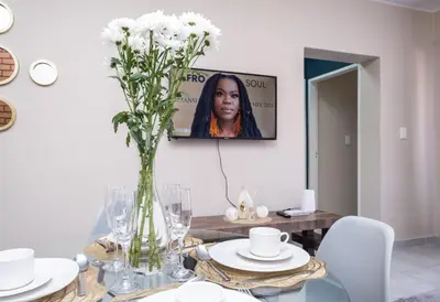 a dining room with a table with a vase of flowers at The Ridge View in Midrand