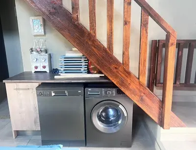 a laundry room with a washer and a staircase at Vivo Per Lei - Marloth Park in Marloth Park