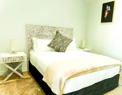a bedroom with a large bed with white sheets and pillows at 8's at Ellipse Waterfall in Midrand