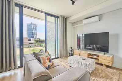 a living room with a couch and a large window at 8's at Ellipse Waterfall in Midrand