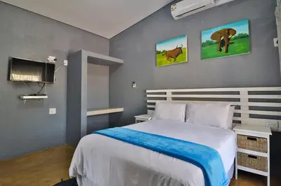 a bedroom with a large bed and a tv at Ilanga Kruger Lodge in Marloth Park
