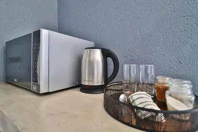a microwave sitting on a counter next to a basket of glasses at Ilanga Kruger Lodge in Marloth Park