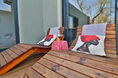 a wooden bench with a glass of wine on a porch at Ilanga Kruger Lodge in Marloth Park