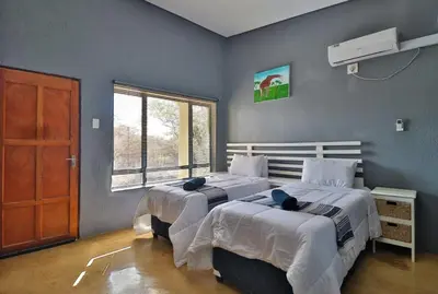 a bedroom with two beds and a window at Ilanga Kruger Lodge in Marloth Park