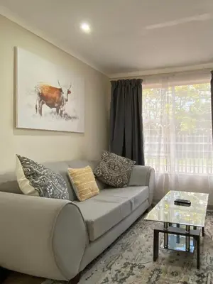 a living room with a couch and a table at Cottage on Keurboom in Midrand