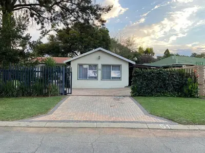 a white house with a fence and a brick driveway at Cottage on Keurboom in Midrand