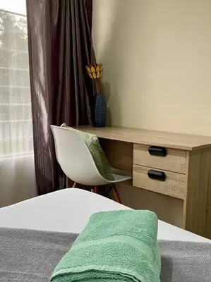 a bedroom with a desk and a bed with a green towel at Cottage on Keurboom in Midrand