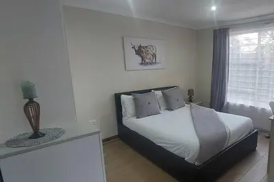 a bedroom with a bed and a table and a window at Cottage on Keurboom in Midrand