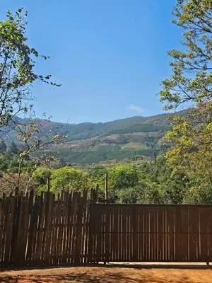 a wooden fence with a view of a mountain at Whispering Creek Mountain Lodge in Magoebaskloof