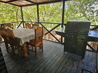 a grill and a table and chairs on a deck at Whispering Creek Mountain Lodge in Magoebaskloof